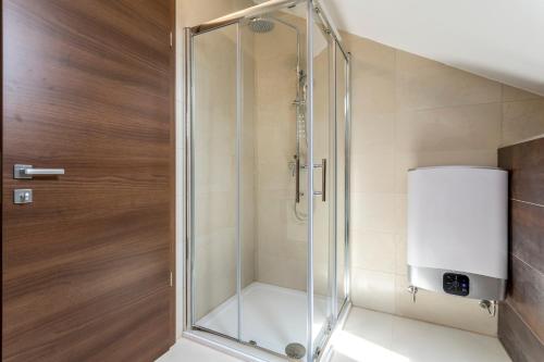 La salle de bains est pourvue d'une douche avec une porte en verre. dans l'établissement Beach Residence with pool and sea view, à Podstrana