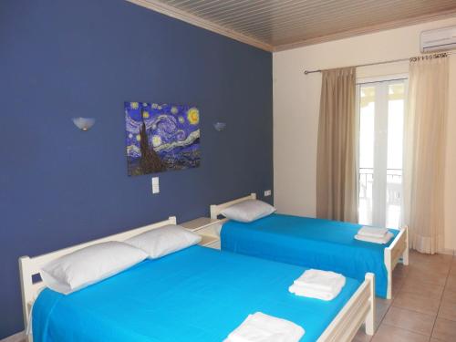 two beds in a room with blue walls at Sea Pebble Studios in Mikros Gialos