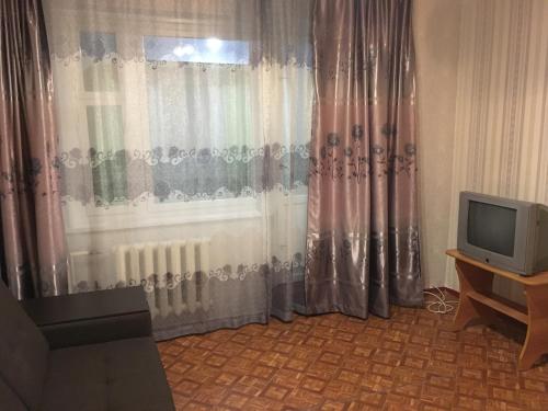 ラザレフスコエにあるApartment on Pobedy streetのテレビ、窓(カーテン付)が備わる客室です。