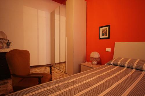 a bedroom with orange walls and a bed and a chair at Affittacamere Da Giorgia in Sampieri