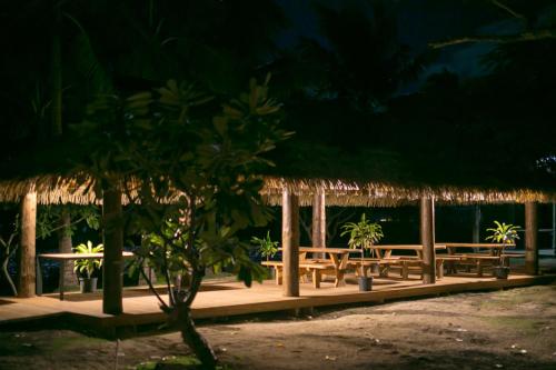 a row of picnic tables with straw umbrellas at night at Serenity Island Resort in Mamanuca Islands