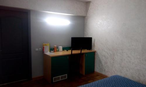 a room with a desk with a television on a wall at Berkana Hotel in Almaty