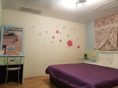 a bedroom with a purple bed and a desk at San Ho Hotel in Taoyuan
