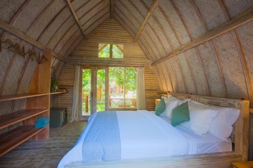 a bedroom with a bed in a wooden cabin at Flowers & Fire Yoga Garden in Gili Islands