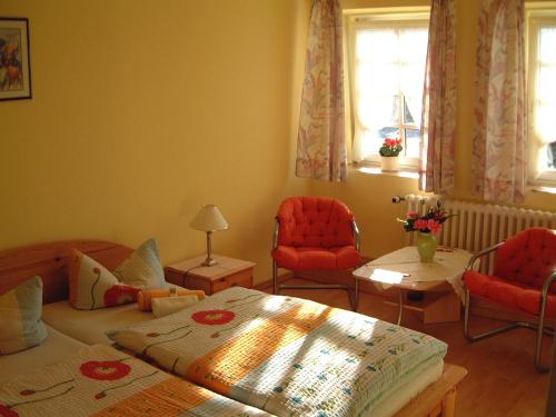 a bedroom with a bed and two chairs and a table at Hotel Auerhahn in Grevenkrug