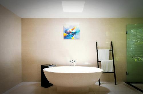 a bathroom with a bath tub and a painting on the wall at Kebun Villas & Resort in Senggigi