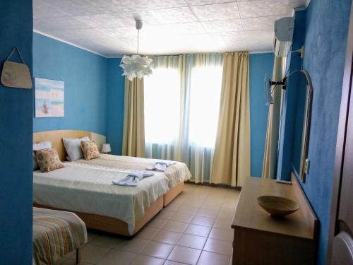 een blauwe slaapkamer met een bed en een raam bij Aura in Primorsko