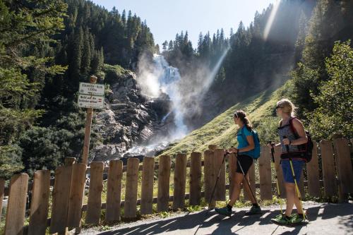 two women standing on a fence looking at a waterfall at Ursprung Panorama Hotel Königsleiten in Königsleiten