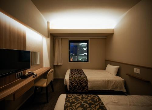 a hotel room with two beds and a television at PORTA INN bentencho in Osaka