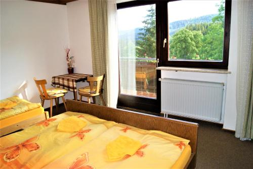 a bedroom with a bed and a window and a table at Penzion Sumavacek in Bayerisch Eisenstein