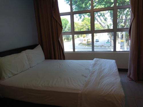 a bed in a room with a large window at Starview Hotel in Lumut