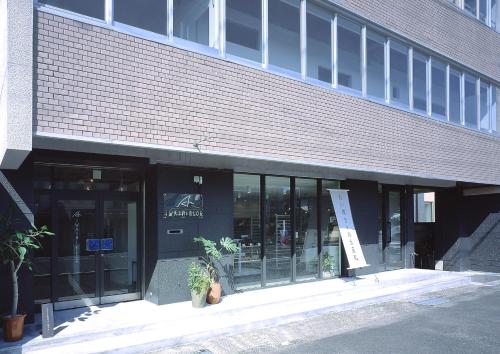 a building with glass doors and plants in front of it at Iwashi Building Hostel in Akune
