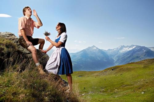 a man and a woman sitting on top of a mountain at Ursprung Panorama Hotel Königsleiten in Königsleiten