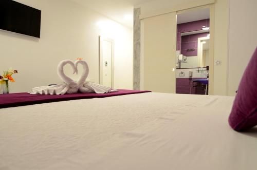 1 cama con 2 toallas blancas en forma de corazón en Hostal Alexis Madrid, en Madrid