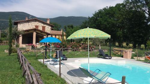 a swimming pool with two chairs and an umbrella at Sulla Strada di San Francesco in Assisi