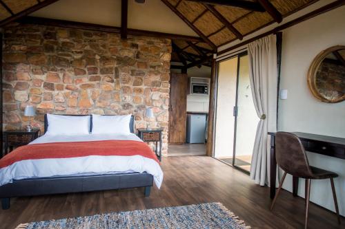 a bedroom with a bed and a stone wall at Ikwanitsha Lodge in Paterson