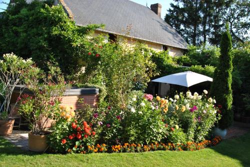 ein Haus mit einem Garten mit Blumen und einem Sonnenschirm in der Unterkunft Clos de Royaucourt in Royaucourt