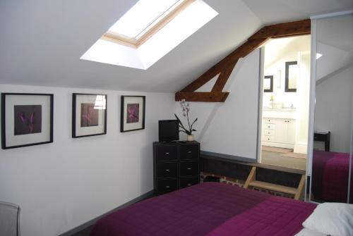 um quarto com uma cama roxa e uma clarabóia em Clos de Royaucourt em Royaucourt