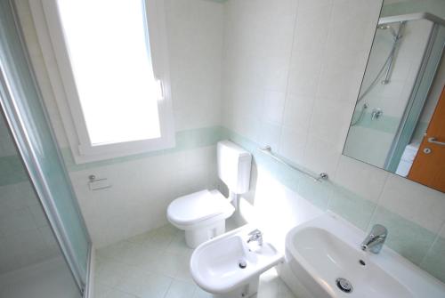 bagno bianco con servizi igienici e lavandino di Villa Palme a Lignano Sabbiadoro