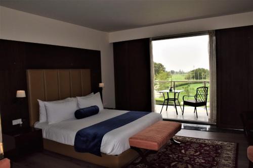1 dormitorio con 1 cama y balcón con mesa en Defence Raya Golf & Country Club, en Lahore