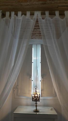 a window with white curtains and a candle on a table at DIANA JARDÍN in Cáceres