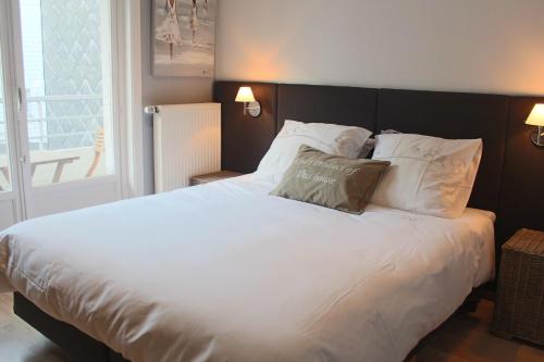 - une chambre dotée d'un grand lit avec des draps et des oreillers blancs dans l'établissement Appartement Azur Oostende, à Ostende