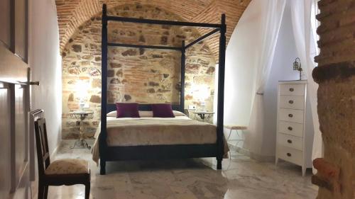1 dormitorio con cama y pared de ladrillo en DIANA JARDÍN en Cáceres