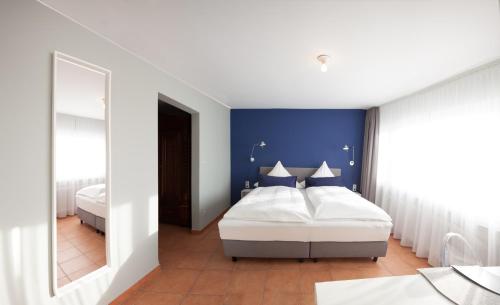 - une chambre avec un lit et un mur bleu dans l'établissement Hotel Fiori, à Bad Soden-Salmünster