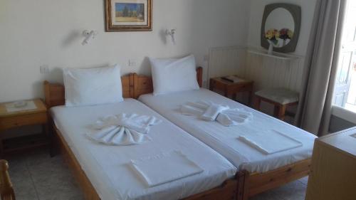 Un dormitorio con dos camas con sábanas blancas y toallas. en Belvedere, en Pythagoreio