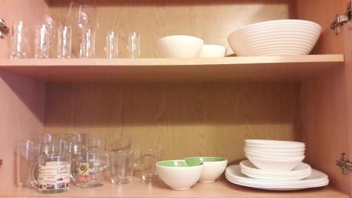 a shelf with plates and bowls and glasses on it at Kalnciema Romantika in Riga