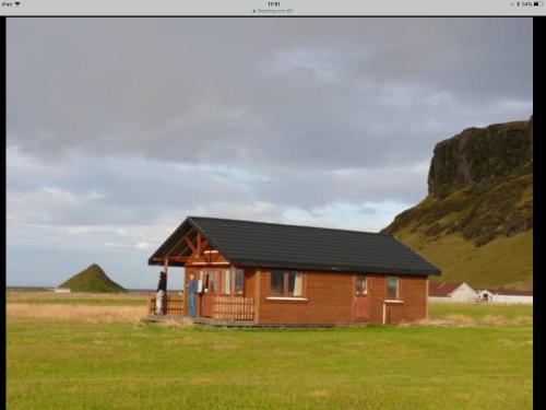 Cabaña de madera pequeña en un campo con montaña en Vellir, en Vík