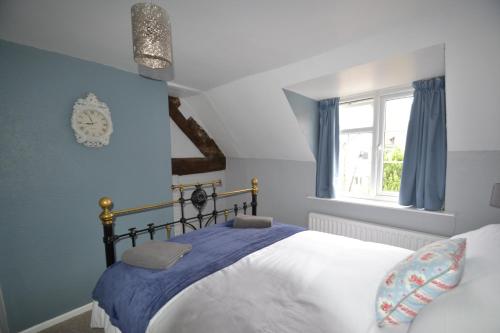 a bedroom with a bed with blue walls and a window at Abbey Cottage in Shrewsbury
