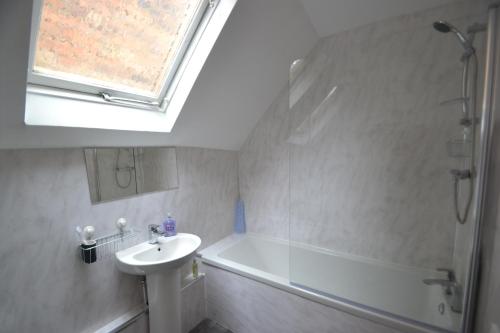een badkamer met een wastafel, een bad en een raam bij Abbey Cottage in Shrewsbury