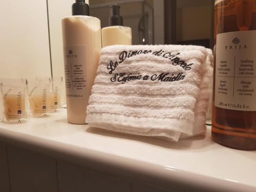 Le Dimore di Angelo في سانت إيوفيميا آ ماييلا: وضع منشفة على منضدة الحمام بجانب زجاجات الصابون
