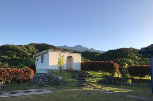a small white house in the middle of a yard at Alps Lodge & Spa in Hokuto