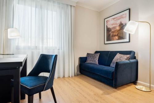 a living room with a blue couch and a desk at Eurostars Gran Hotel Lugo in Lugo