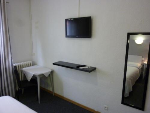 a room with a mirror and a tv on the wall at Hotel les Glycines in Prades