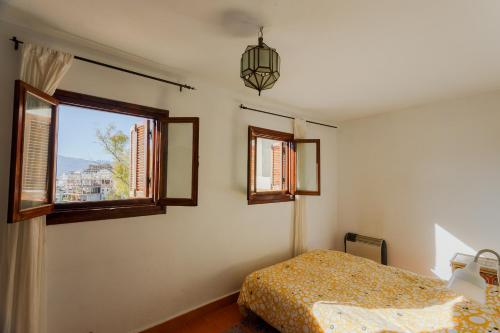 - une chambre avec un lit et 2 fenêtres dans l'établissement Dar Carlos, à Chefchaouen