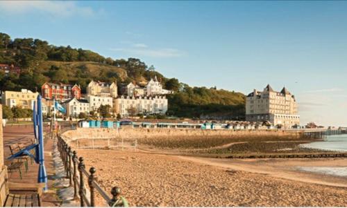 een persoon op een strand met gebouwen op de achtergrond bij 7 Llewelyn Avenue in Llandudno