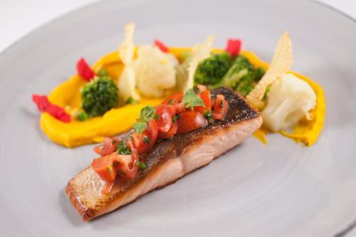a plate of food with a piece of fish and vegetables at Mediteran Hotel & Resort in Budva