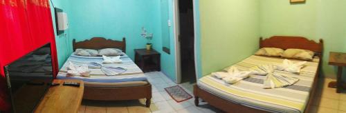 two twin beds in a room with a mirror at Jun and Carol Beach Cottages in Pagudpud