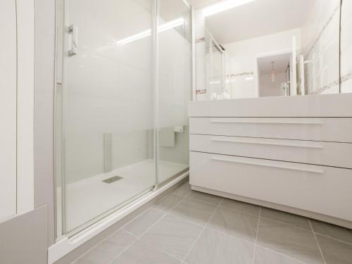 ニースにあるWelkeys - Fabron Apartmentの白いバスルーム(シャワー、ガラスドア付)