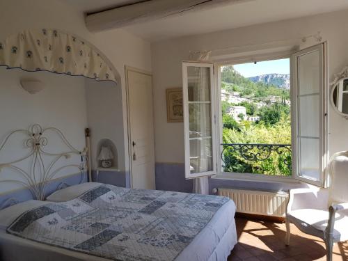 une chambre avec un lit et une grande fenêtre dans l'établissement Bastide des Oliviers, à Moustiers-Sainte-Marie