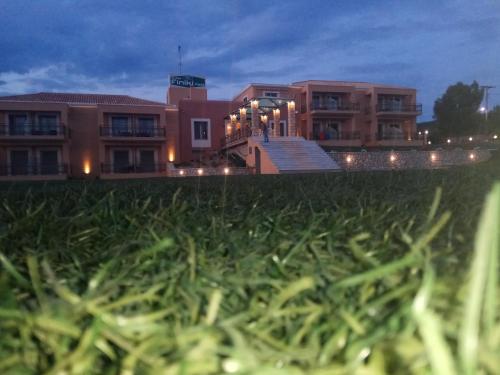 a building with a field of grass in front of it at Finiki Plaza in Methoni