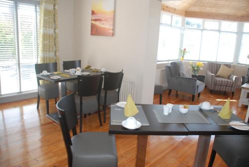 un comedor con mesas, sillas y ventanas en Tuskar House by the Sea, en Rosslare