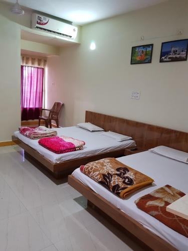 a room with two beds and a chair in it at Hotel Shri Radhe Krishna in Godarpura