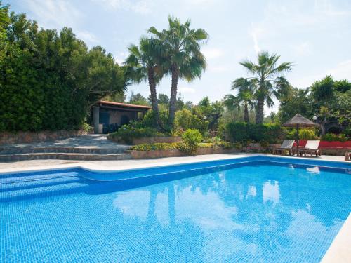 una piscina en un patio con palmeras en Belvilla by OYO Can Jurat, en Ses Paisses