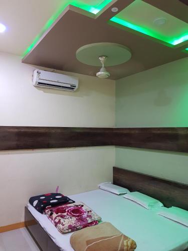 a room with a bed and a ceiling with green lights at Hotel Shri Radhe Krishna in Godarpura