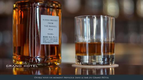 a bottle of whiskey next to a glass of alcohol at Grand Hôtel Bénodet Abbatiale Riviera Bretonne in Bénodet