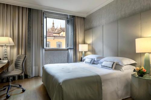 a bedroom with a large bed and a desk and a window at Rosa Grand Milano - Starhotels Collezione in Milan